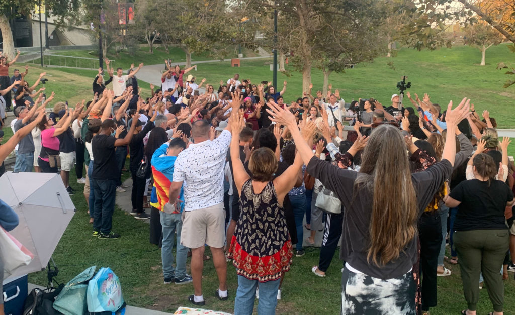 A crowd holds hands to the sky during an open air session of Kathryn Krick's ministry in Los Angeles.